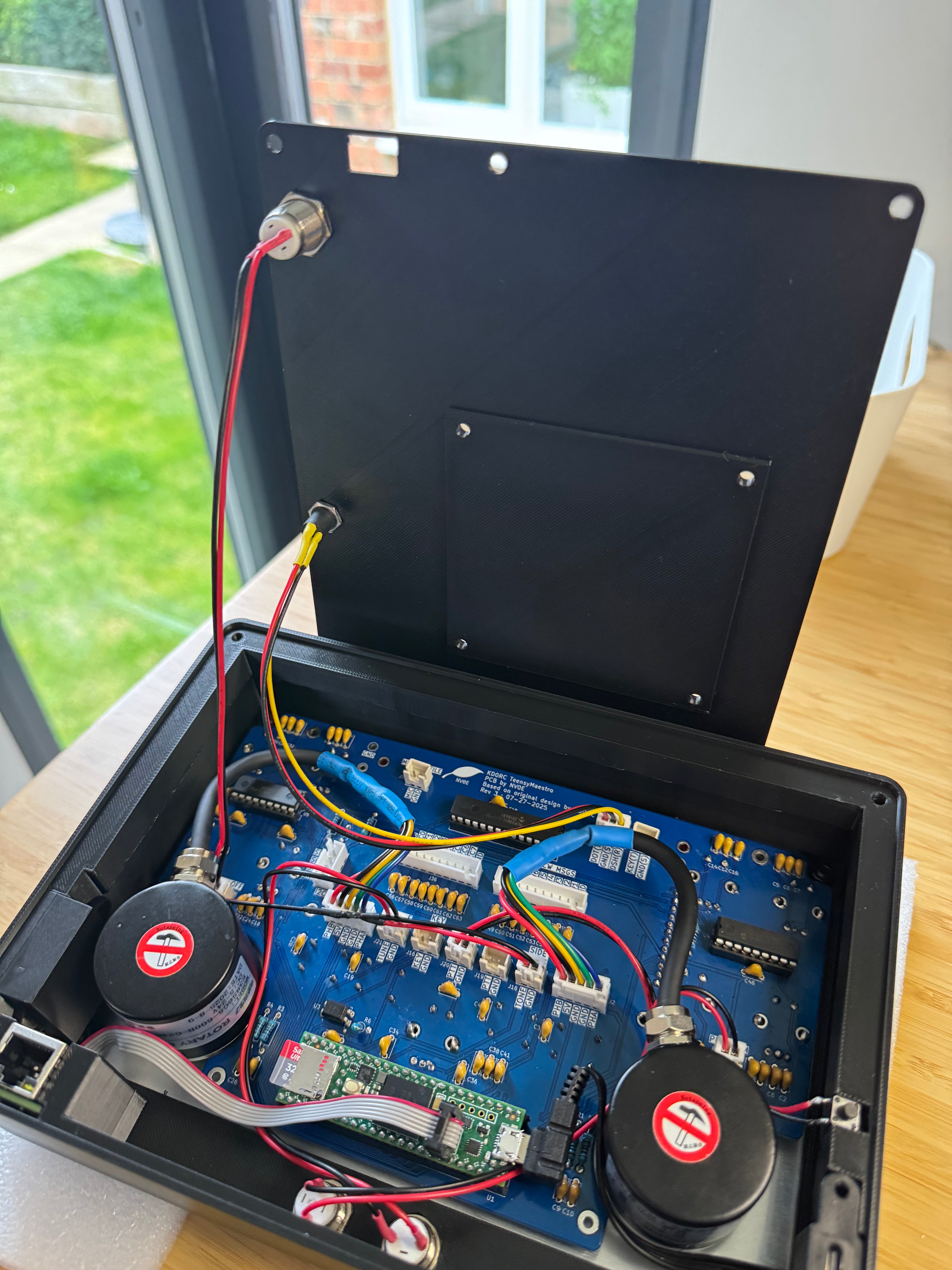 The case open with the back panel lifted up, its power button and socket wired to the PCB, and all the leads connected